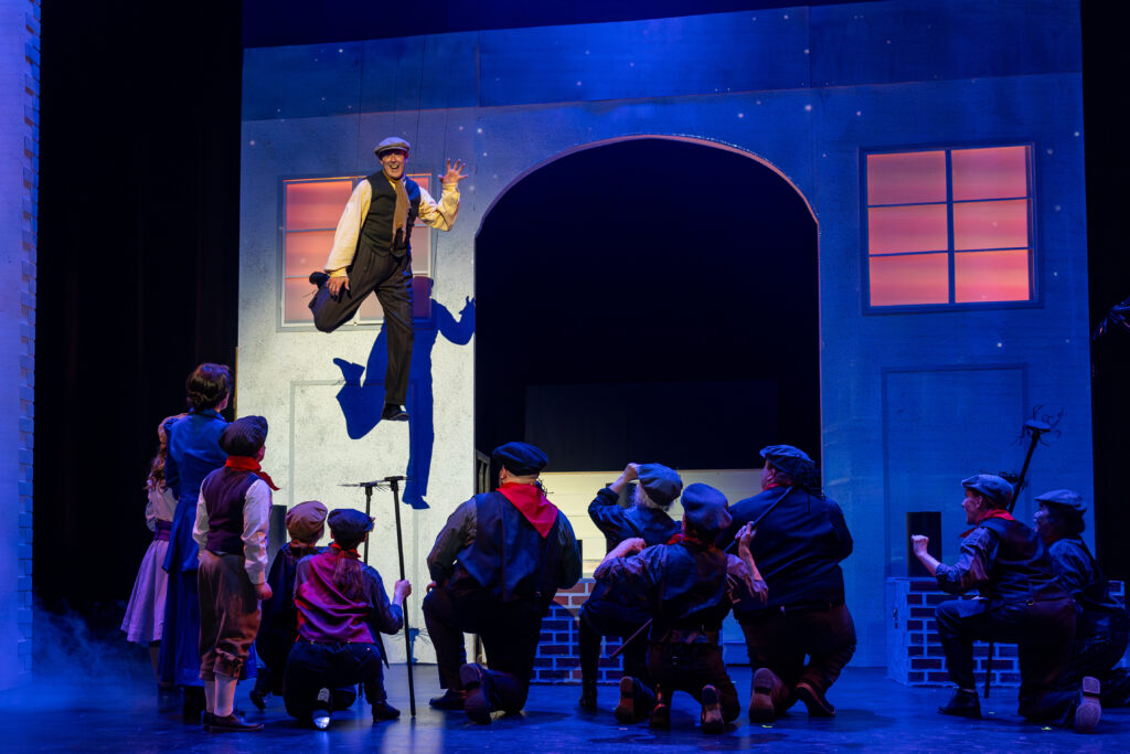 Man rising above cast members in theatre production